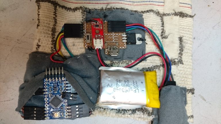 Haptic compass electronics: Arduino Pro Mini, magnetometer, battery, and charging board laid out on the compression fabric