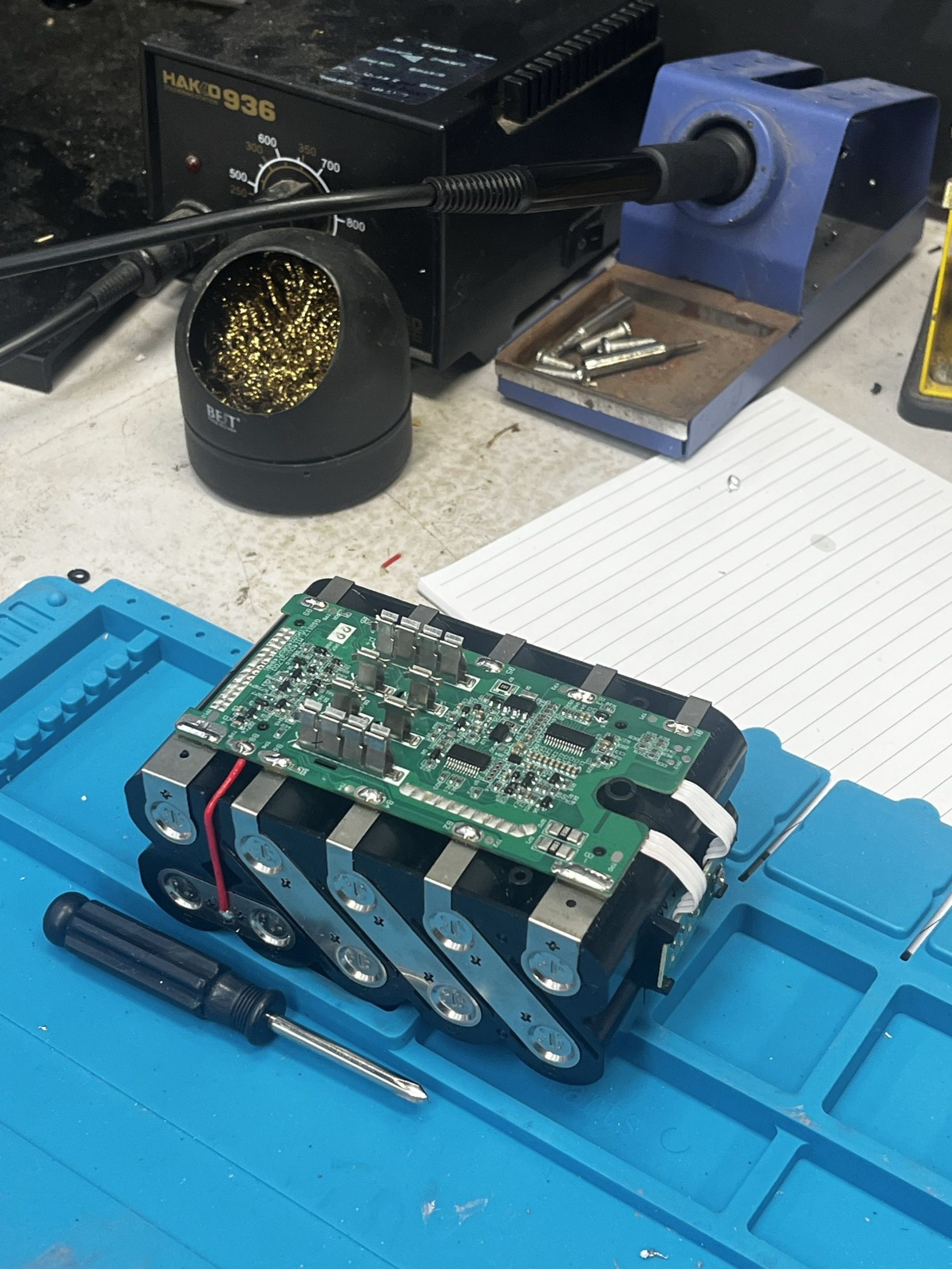 Workbench with Sequre SW3 spot welder, battery pack in progress, and genuine Makita battery for reference